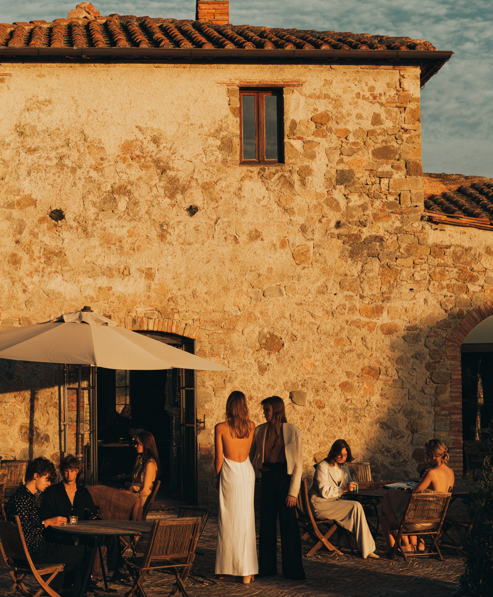 Guests gathered at a stone Tuscan villa courtyard at golden hour